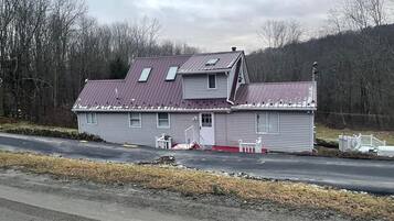 A two-story house with a red roof, a front porch, and a garage.