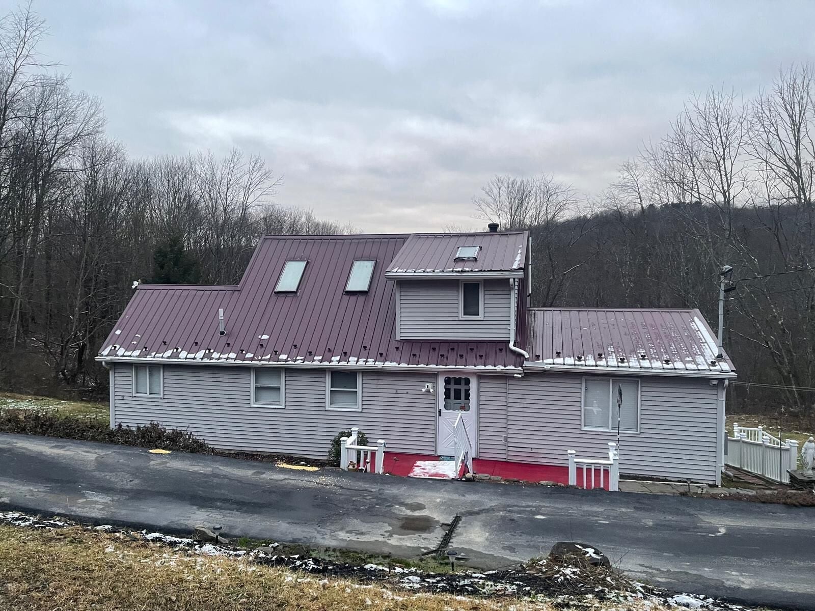 A two-story house with a red roof and a small porch.