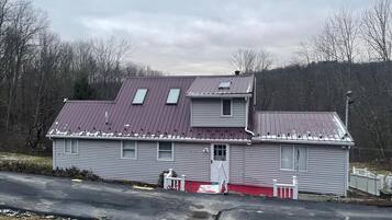 A two-story house with a red roof and a small porch.