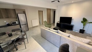 A modern living space with a kitchen, dining area, and a seating area with a TV. - Comfort SpataAir Stay (Spata)