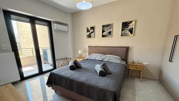 A modern bedroom with a large bed, a bedside table, a lamp, and artwork on the wall. - Comfort SpataAir Stay (Spata)