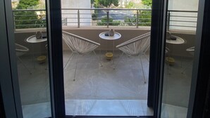 A balcony with two chairs and a table, a view of buildings and greenery, and a clear sky. - Comfort SpataAir Stay (Spata)