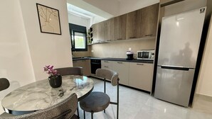 A modern kitchen with a marble table, grey chairs, a stainless steel refrigerator, and wooden cabinets. - Comfort SpataAir Stay (Spata)