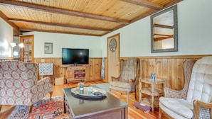 A cozy living room with wooden beams, a television, patterned chairs, and a coffee table. - Near Mississippi River! Countryside Family Retreat (Eastman)