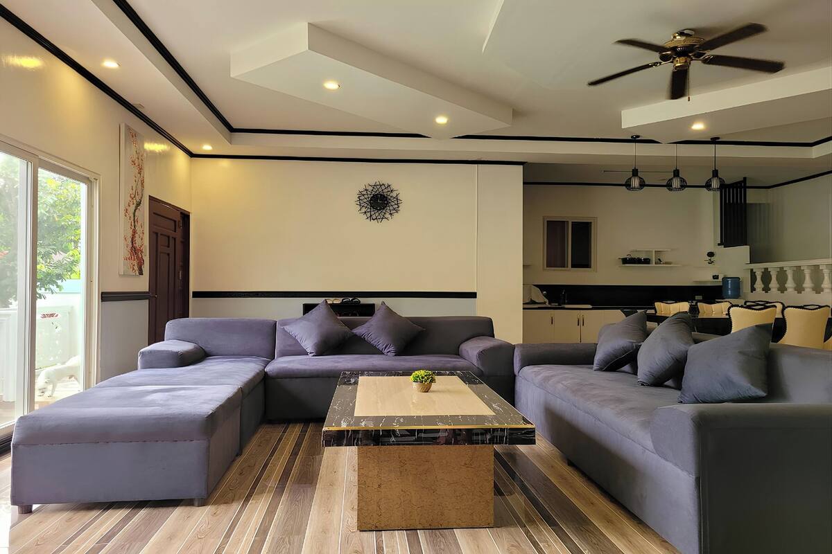 A modern living room with a sectional sofa, a coffee table, and a ceiling fan.