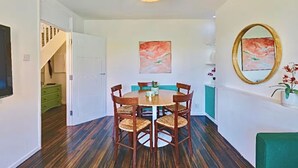 Uma sala de jantar com uma mesa redonda, quatro cadeiras e duas pinturas na parede.