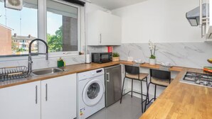Uma cozinha moderna com máquina de lavar, micro-ondas e pia.