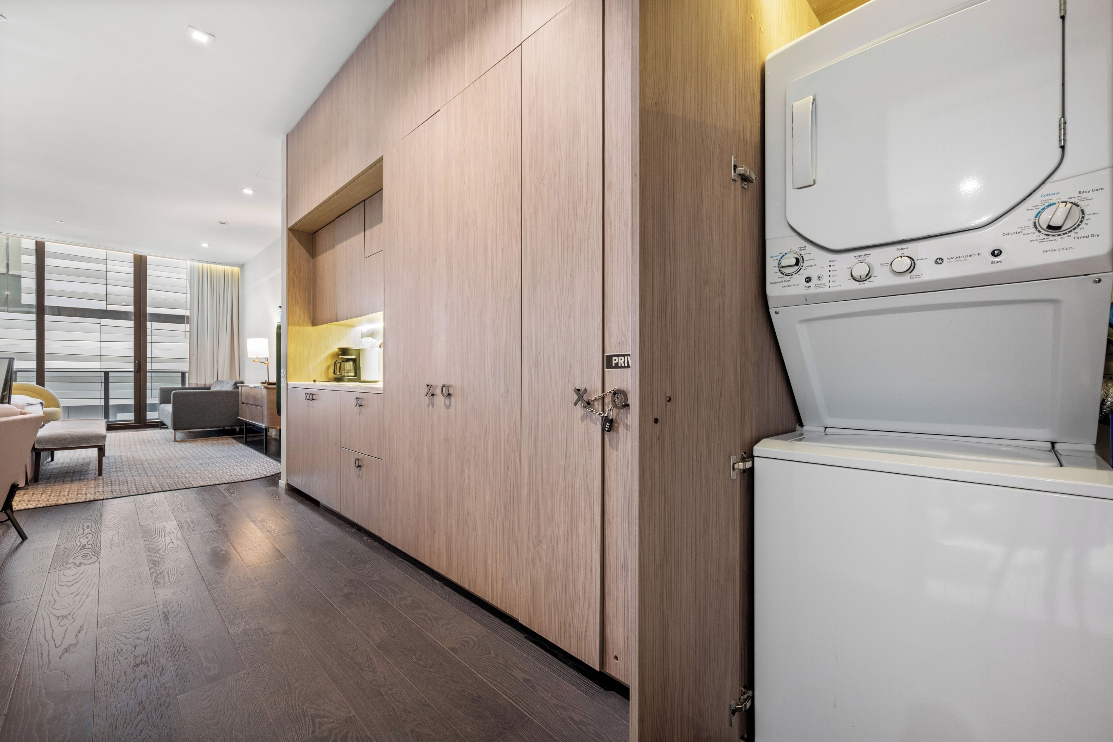 A modern kitchen with wooden cabinets, a built-in oven, and a dining area with a sofa and table.