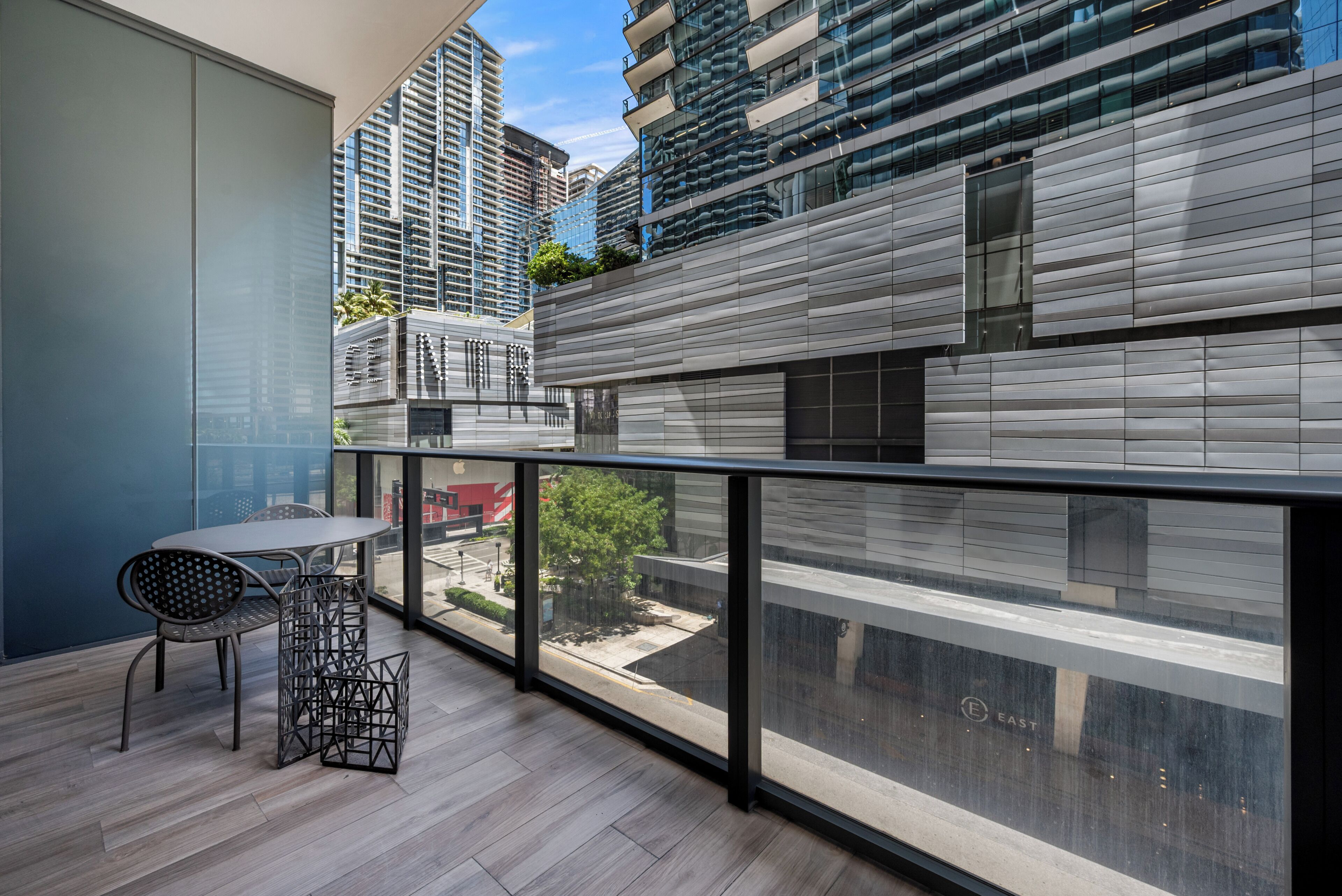 A balcony with a table and chairs, a view of a cityscape, and a building with a modern design.