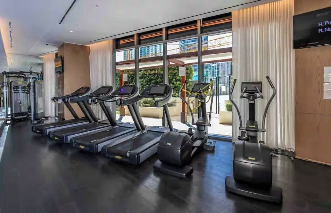 Une salle de sport équipée de tapis de course, de vélos elliptiques et d’un vélo d’appartement.