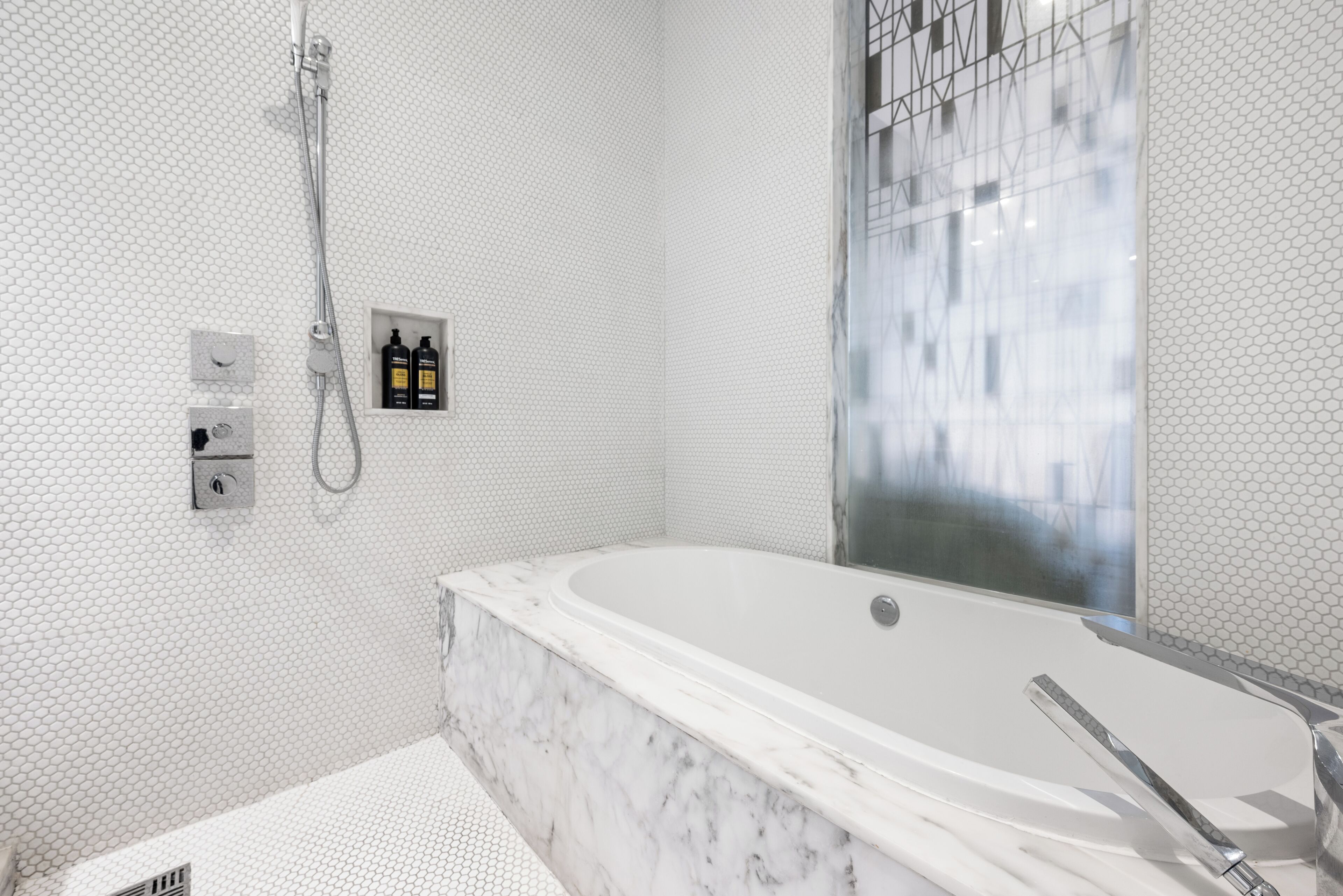 A modern bathroom with a large bathtub, a shower, and a glass-enclosed shower area.