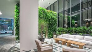 An indoor seating area with a white sofa, two wooden tables, and a cushioned chair. - Lux Brickell by Palermo Home Miami (Miami)