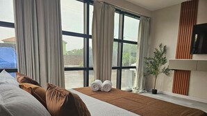 Habitación de hotel con una cama grande, dos almohadas, una manta y una planta en maceta.