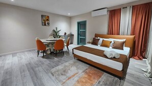 Una habitación de hotel moderna con una cama grande, un escritorio con sillas y una mesa de comedor.