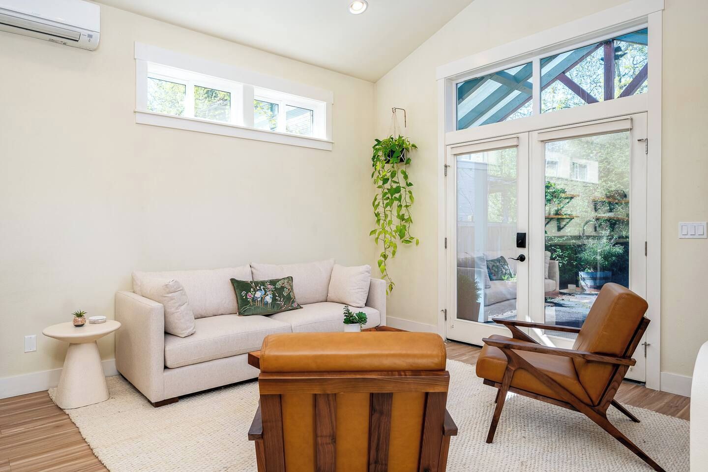 A living room with a sofa, a wooden ottoman, a side table, a hanging plant, and a chair.