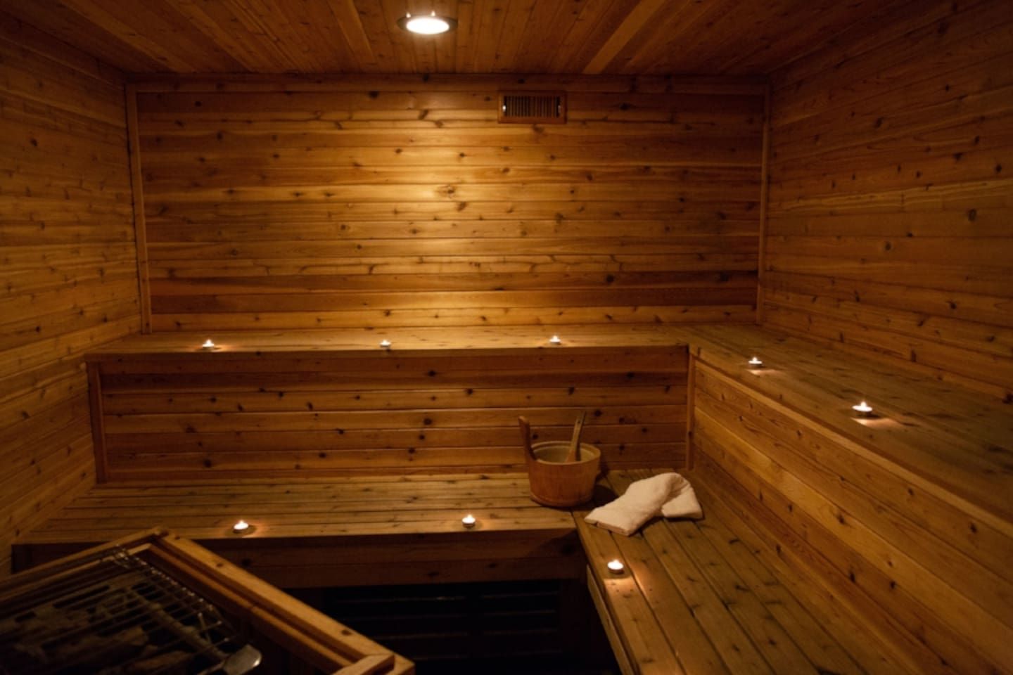 Un sauna con paredes, bancos y un cubo de madera.