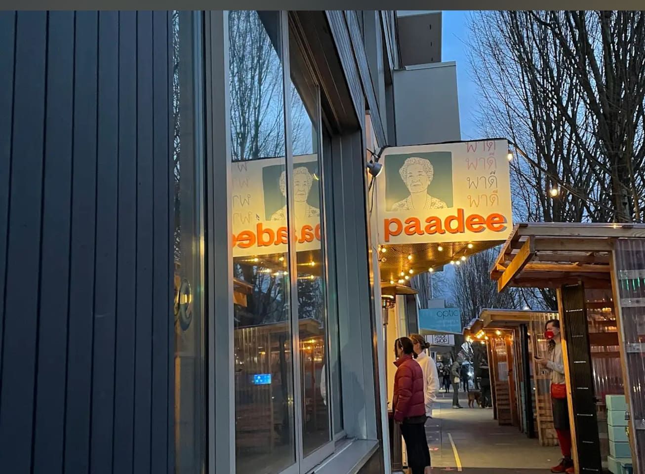 A storefront with a sign that reads 'paadee' and a reflection of a person on the glass window.