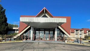 A building with a red roof, a covered entrance, and a sign indicating a clearance of 9 feet. - Rusina inn (Colorado Springs)