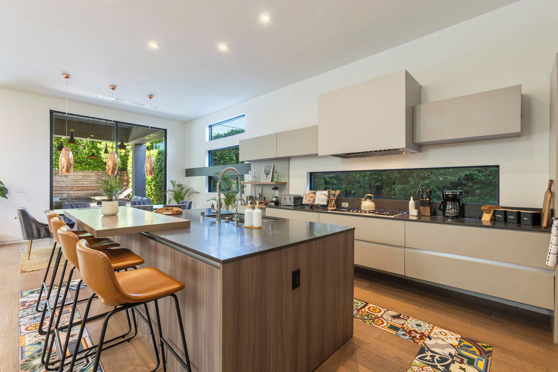 Een moderne keuken met een centraal eiland, barkrukken en uitzicht op groen.