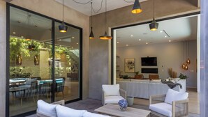 Un espace extérieur moderne, aménagé avec des meubles en osier, une table basse et des luminaires suspendus.