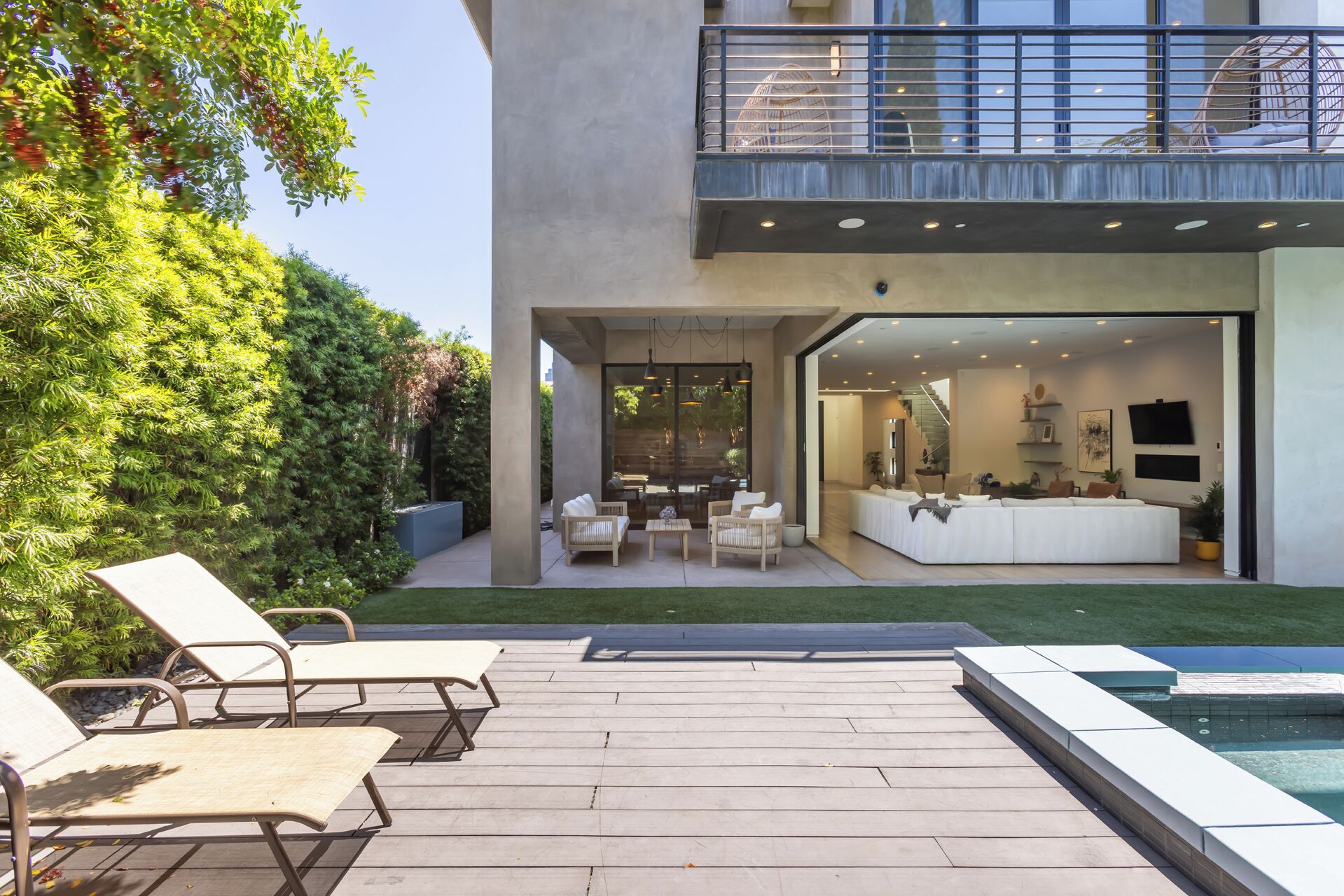 A modern house with a patio, outdoor seating, and a pool.