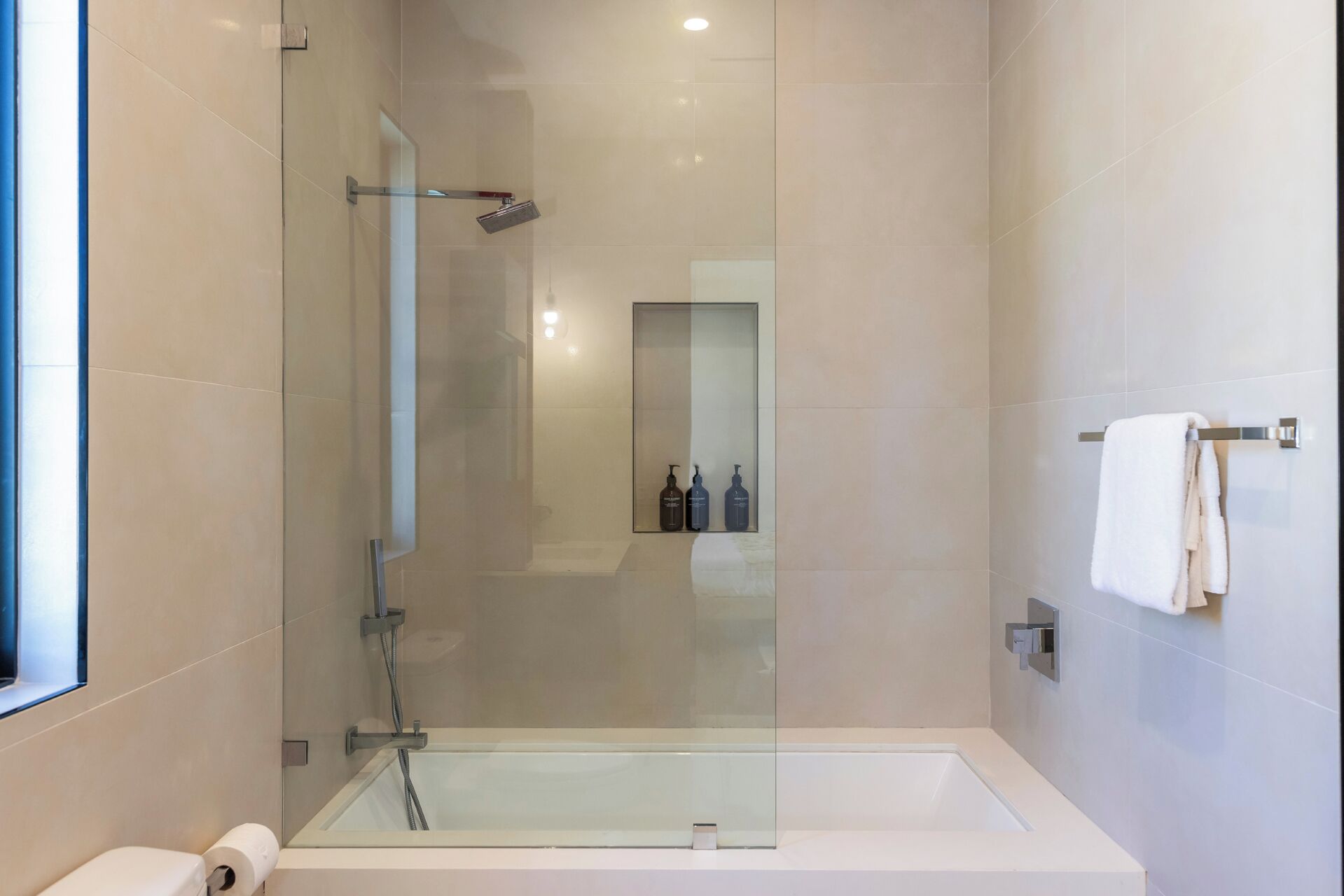 Une salle de bain moderne avec une douche à l’italienne, une baignoire blanche et un porte-serviettes.