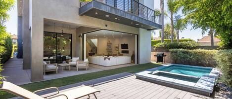 A modern two-story house with a patio, outdoor seating, and a swimming pool.