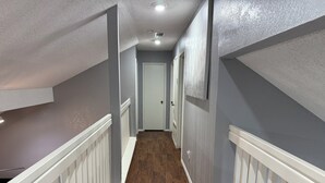 A hallway with wooden flooring, white railings, and grey walls. - Cozy 4 bedroom home in Grand Prairie,TX (Grand Prairie)