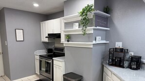 A modern kitchen with white cabinets, a black stove, and a coffee station. - Cozy 4 bedroom home in Grand Prairie,TX (Grand Prairie)