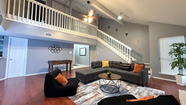 A spacious living room with a large sectional sofa, a coffee table, and a staircase leading to an upper level. - Cozy 4 bedroom home in Grand Prairie,TX (Grand Prairie)