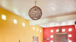 Ein Wohnzimmer mit einer Sofagarnitur, einer dekorativen Pendelleuchte, einem gemusterten Teppich und einer roten Akzentwand.
