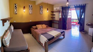 Ein Hotelzimmer mit Bett, Sofa, Kunstwerken an den Wänden und Blick ins Freie.