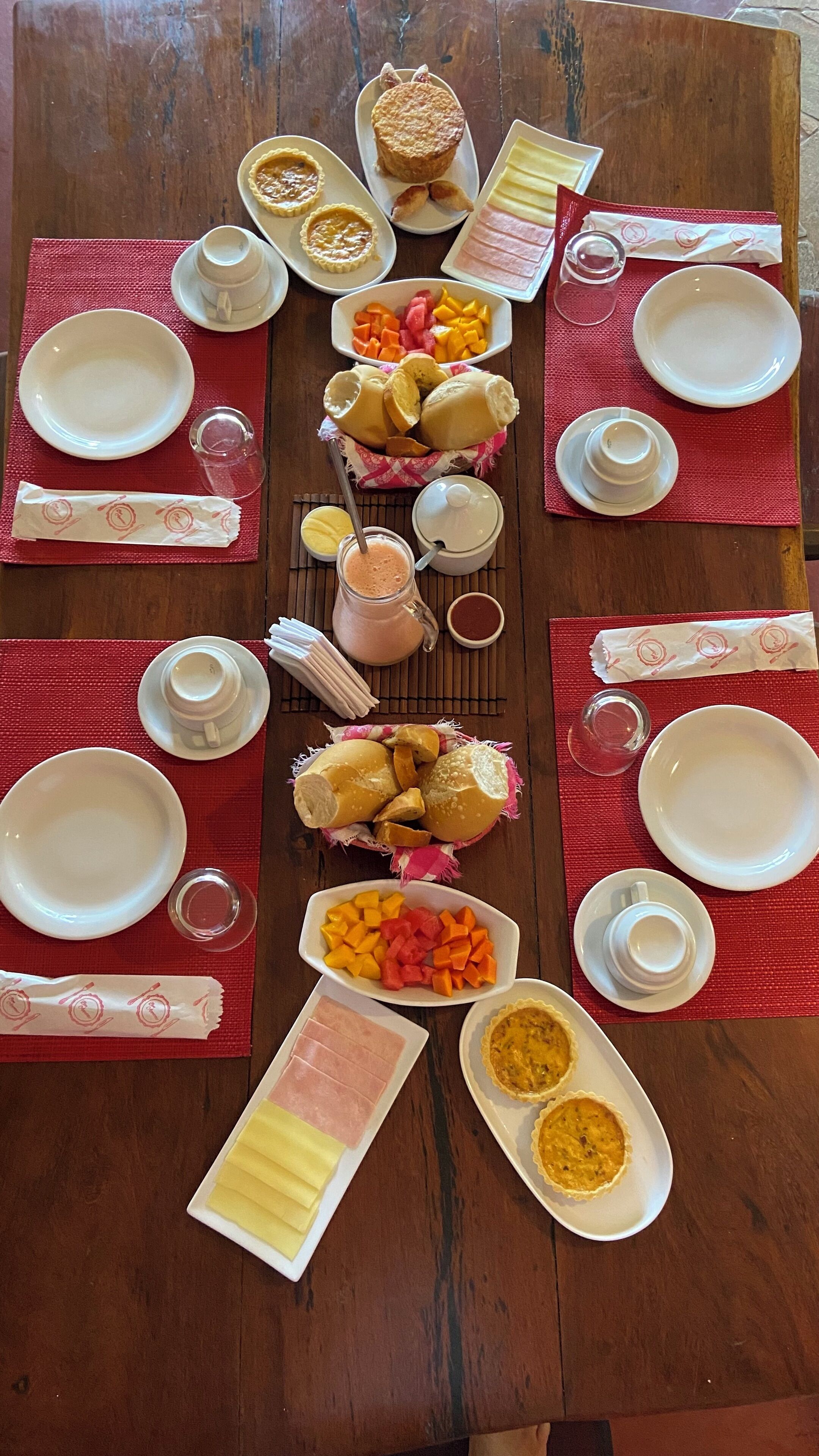 Un tavolo da pranzo in legno apparecchiato con piatti, ciotole e diversi alimenti.