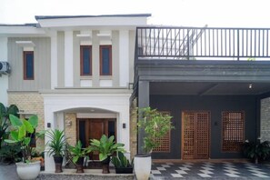 A two-story building with a front entrance, a balcony, and a covered area with a checkered floor. - Illusion Homestay (Ngaglik)