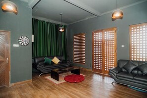 A living room with a sofa, a red rug, and a wooden floor. - Illusion Homestay (Ngaglik)