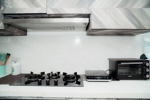 A kitchen with a gas stove, a toaster oven, and a microwave. - Illusion Homestay (Ngaglik)