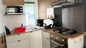 A compact kitchen with a microwave, coffee maker, and gas stove. - Mobile home 6/8 pers camp 4 stars (Saint-Jean-de-Monts)