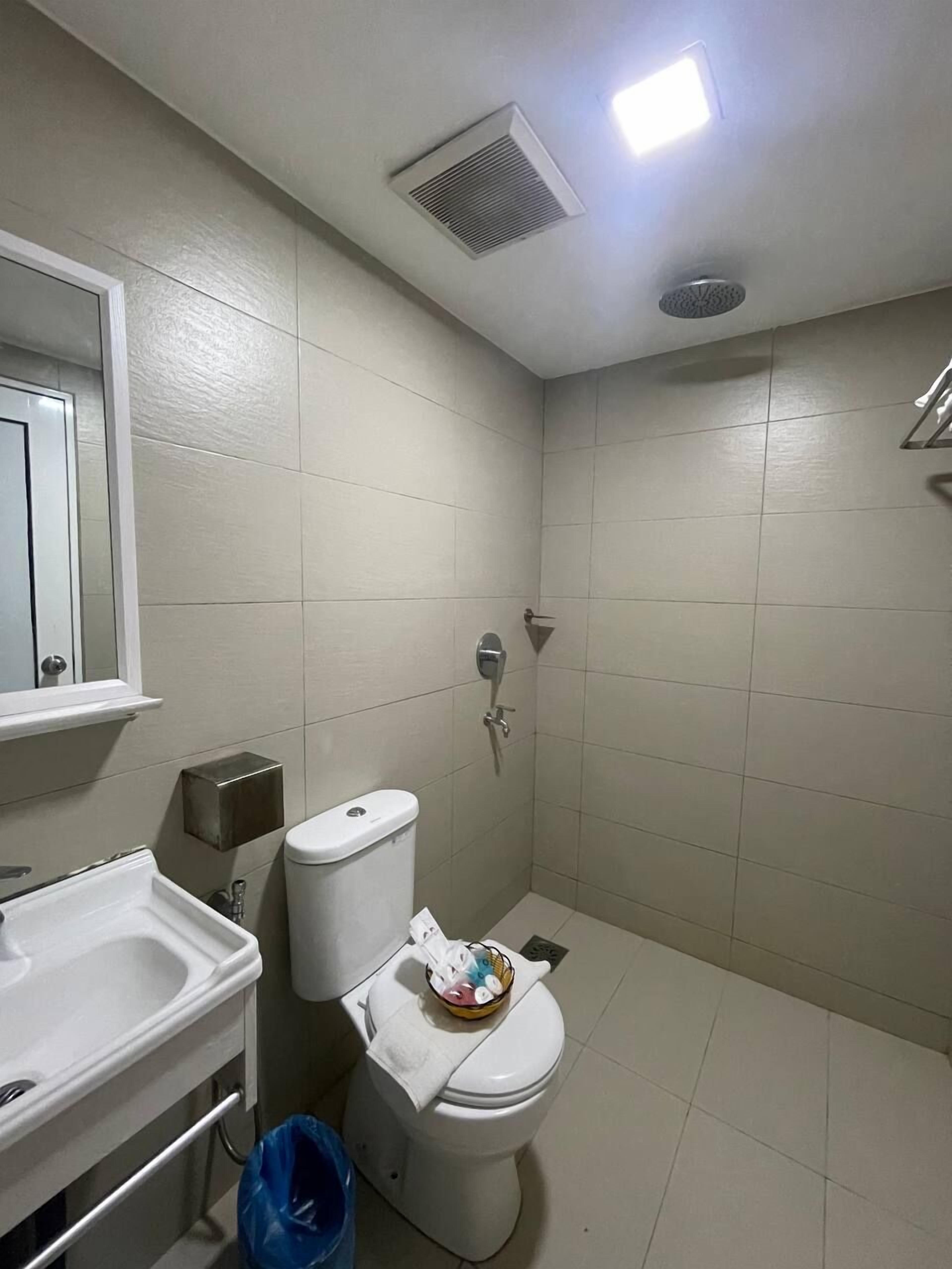 A small bathroom with a toilet, sink, and shower.