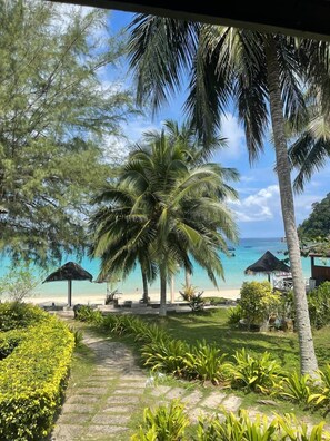 A tropical beach resort with palm trees, a pathway, and beach umbrellas. - Perhentian Resort Island PIR - BlueStar (Pulau Perhentian Besar)