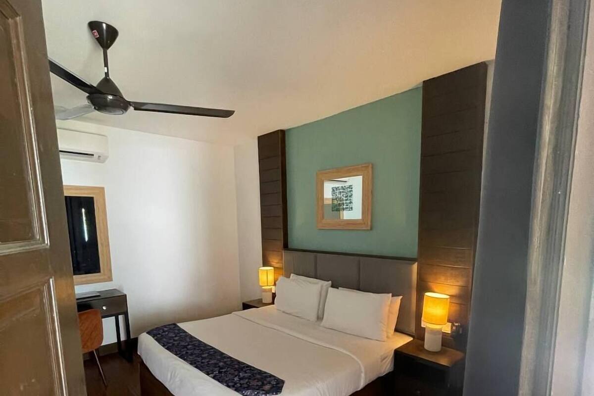 A bedroom with a bed, bedside lamps, a ceiling fan, and a framed picture on the wall.