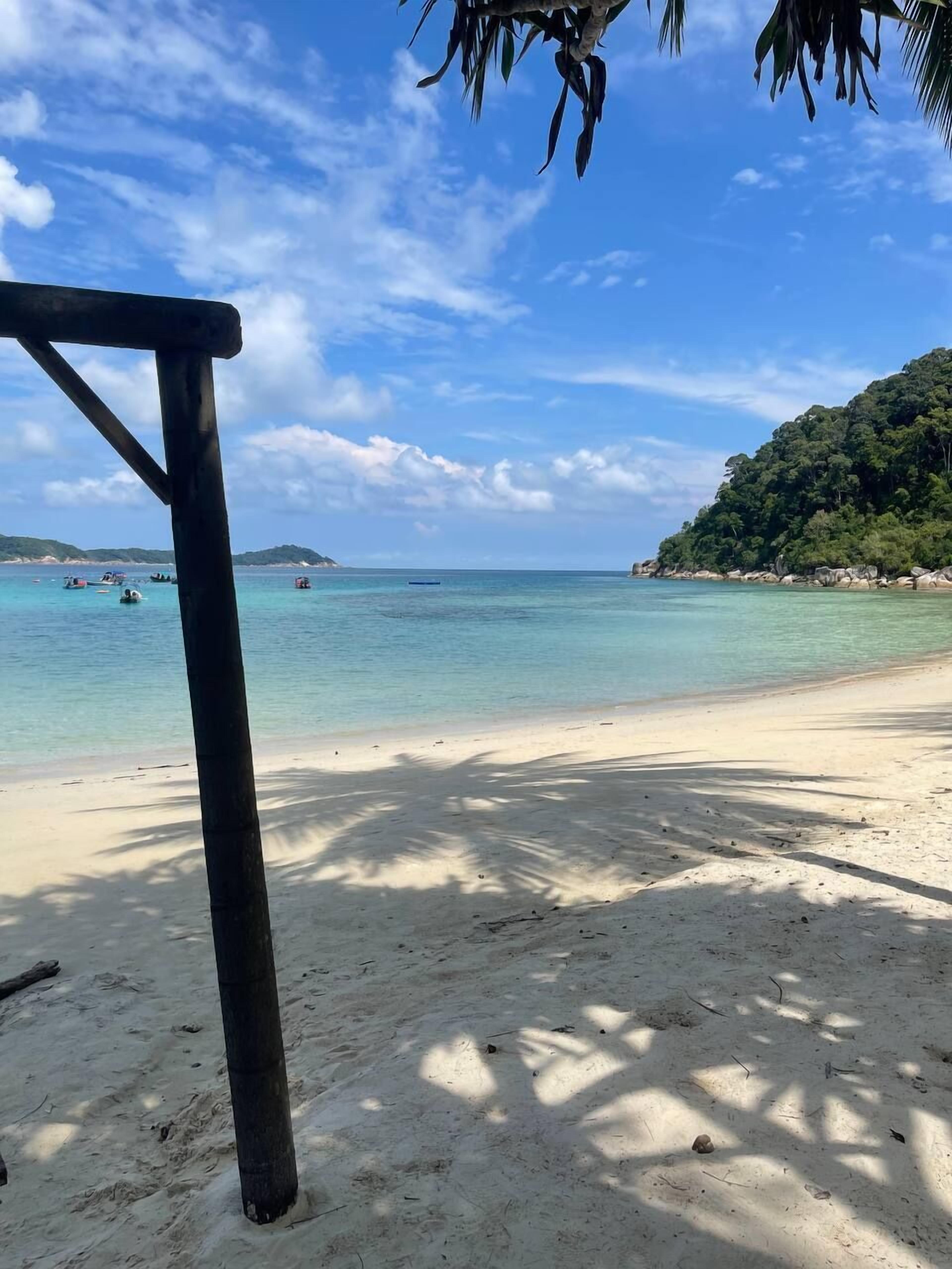 A beach with clear turquoise water, a sandy shore, and a wooden structure.