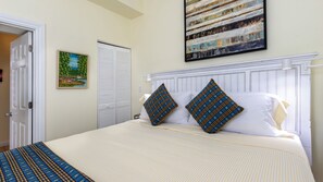 A neatly made bed with a white headboard, two decorative pillows, and a striped blanket. - Authors Retreat (Key West)