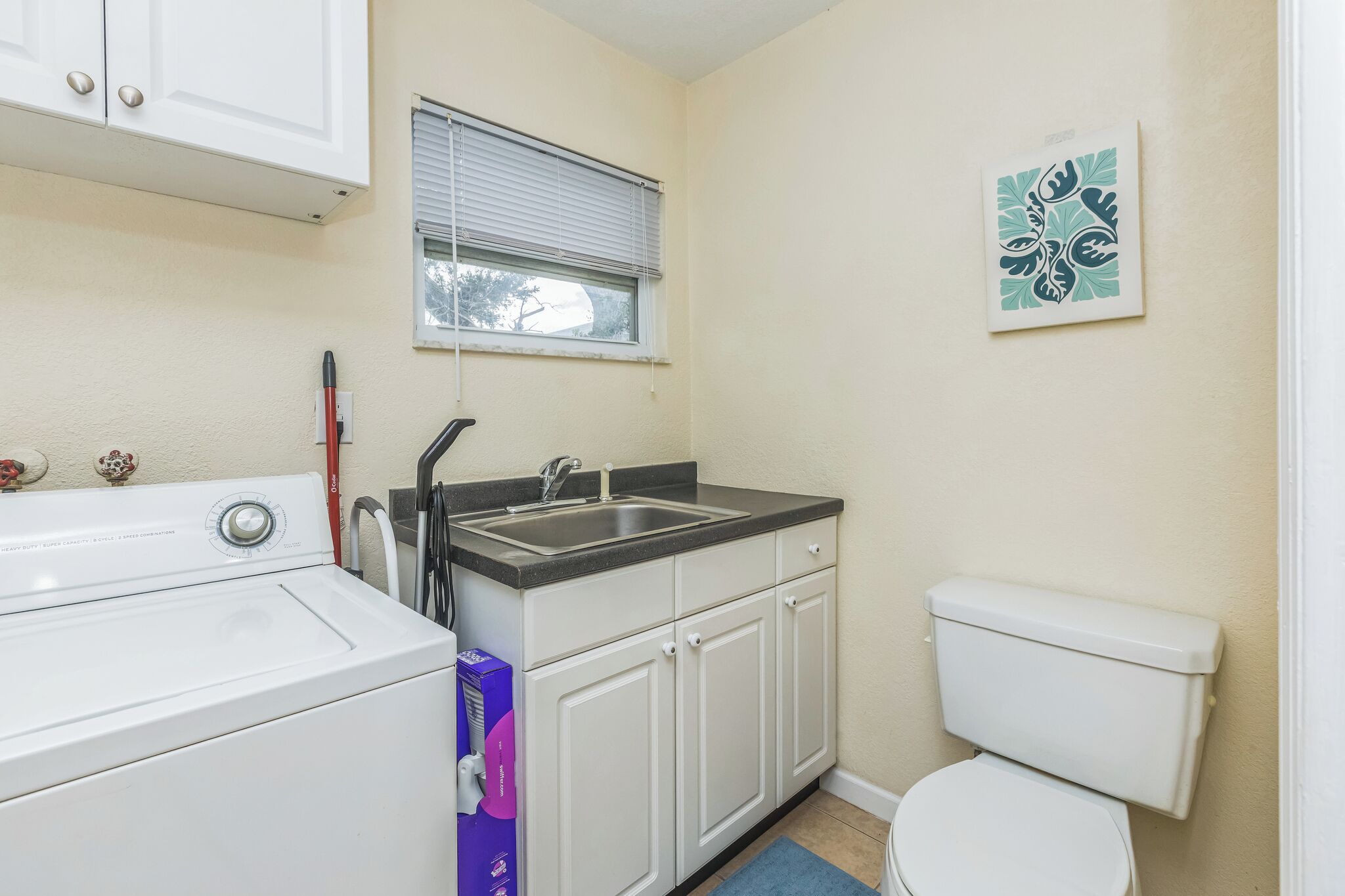A compact kitchen with a washing machine, a sink, and a toilet.