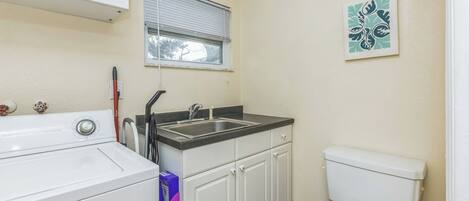 A compact kitchen with a washing machine, a sink, and a toilet.