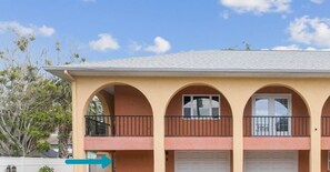 A two-story building with an outdoor shower and beach gear. - NEW Luxe Condo; Sand, Sea, & Sunset at IRB; Steps 2 Beach; SMART TVs; PRIVATE (Indian Rocks Beach)