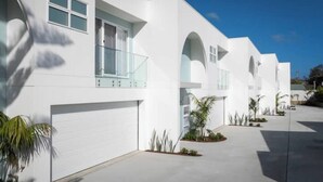 A modern white building with multiple garage doors, large windows, and a clear sky.