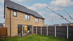 A two-story house with a brick exterior, a metal roof, and a fenced backyard. - Modern Home in Quiet Environment (Corby)