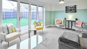 A living room with a glass coffee table, two sofas, and a grey ottoman. - Modern Home in Quiet Environment (Corby)