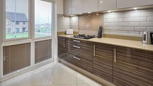 A modern kitchen with a large window, a gas stove, and a coffee maker. - Modern Home in Quiet Environment (Corby)