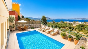 Une piscine avec des chaises longues et vue sur la mer.